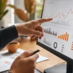 Mains analysant un tableau de bord de performance web avec graphiques de trafic sur un écran d'ordinateur