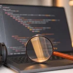 Loupe posée devant un ordinateur portable affichant du code HTML aux lignes indentées en niveaux, avec un casque audio à côté, pour illustrer les balises H1, H2, H3 et l’accessibilité